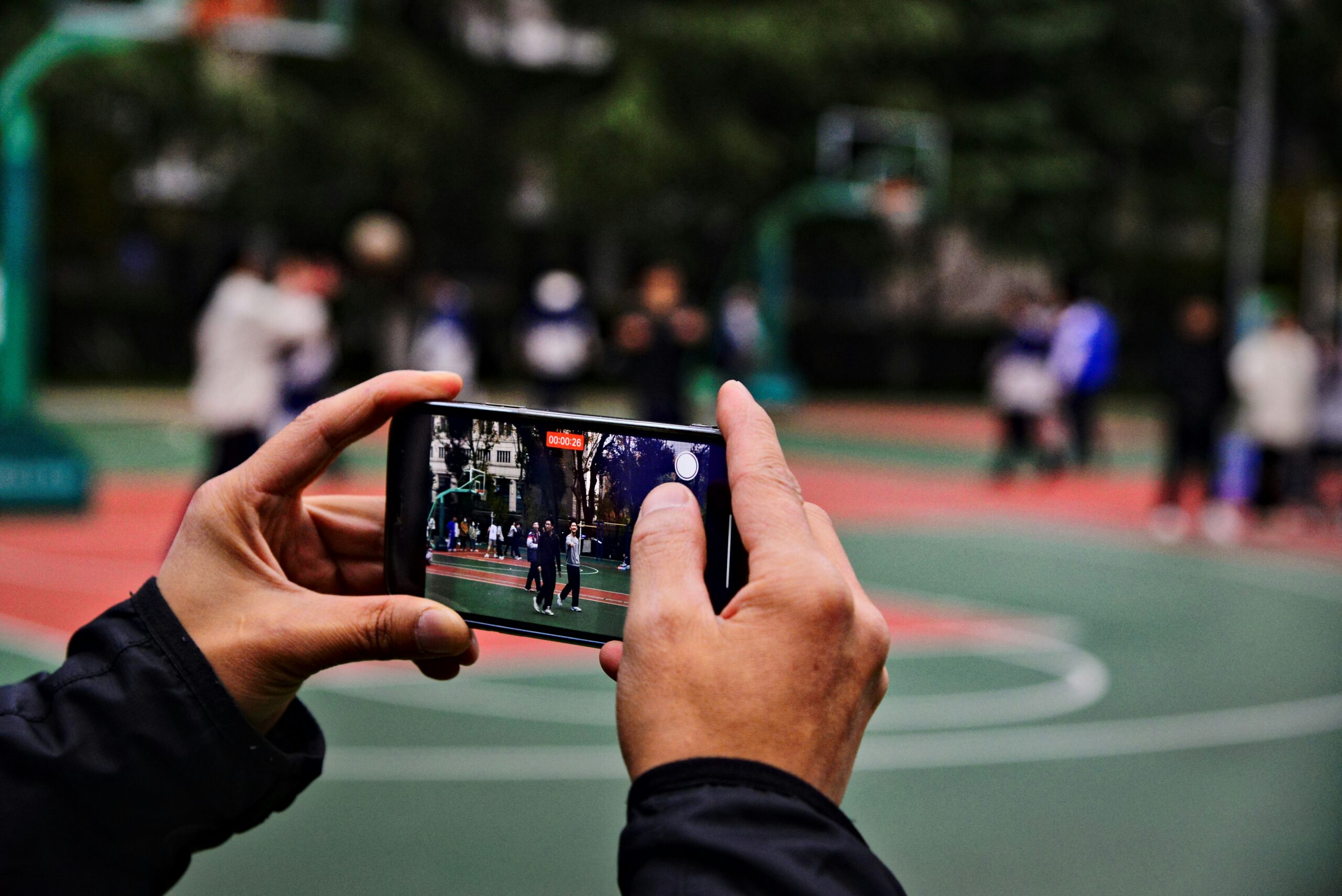Athlete recording a highlight reel on a mobile phone at a basketball court